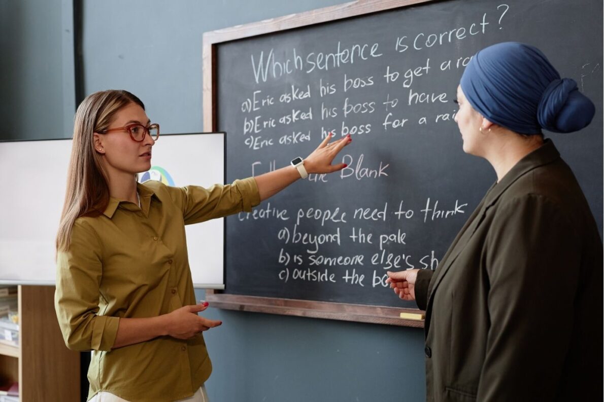 A teacher and her adult learner in front of the blackboard in class.