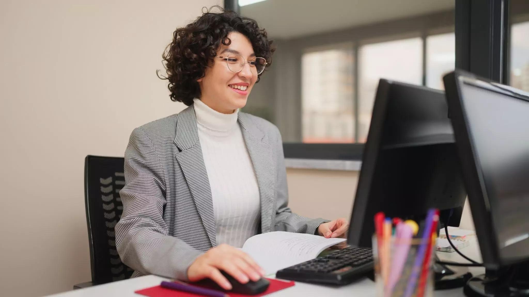 a teacher sitting at her desk working on her computer