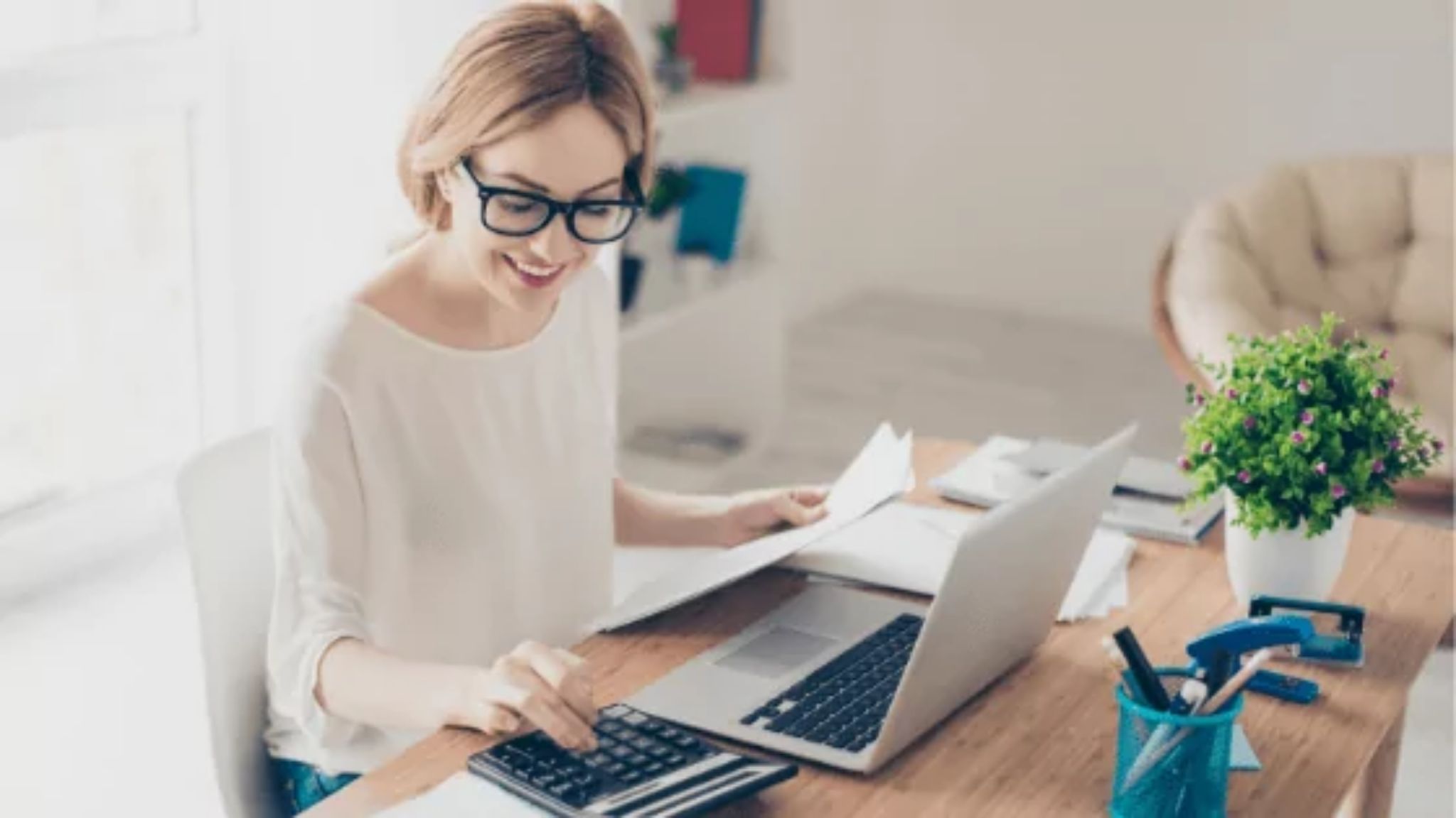 A woman using a calculator and a laptop to manage her business' cash flow