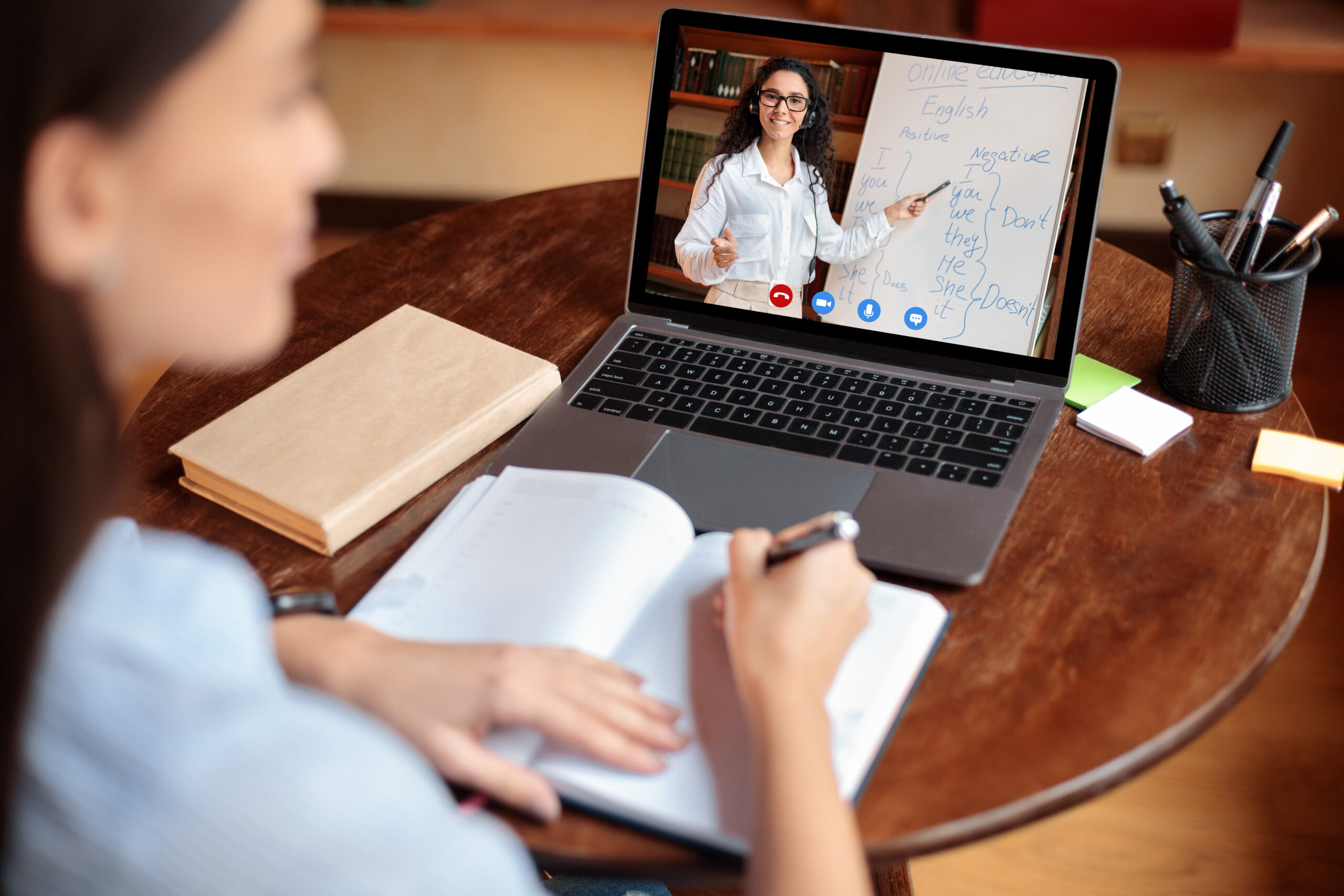 Student using laptop having online class with teacher, over shoulder